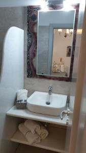 a bathroom with a sink and a mirror and towels at Katerina Apartments & Studios in Naousa