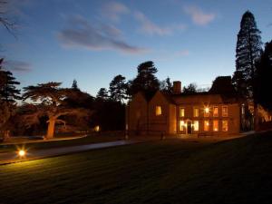 Une grande maison éclairée la nuit dans l'établissement Flitwick Manor Hotel, BW Premier Collection, à Flitwick