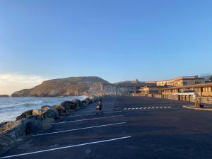 a person walking down a road next to the ocean at Sea Breeze Motel in Pacifica