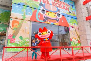 a young boy standing next to a mascot in front of a store at Hotel Ocean (Kokusai-Dori) in Naha