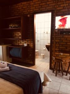 um quarto com uma cama e uma televisão de ecrã plano em Pousada das Hortênsias em São Bonifácio