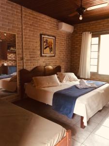 a bedroom with two beds and a brick wall at Pousada das Hortênsias in São Bonifácio