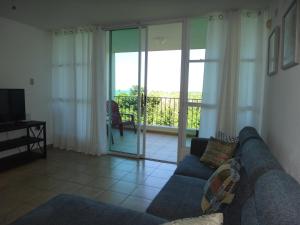 sala de estar con sofá y puerta corredera de cristal en Stunning Sunset View, Walking distance to private beach en Cabo Rojo