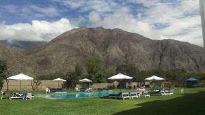 a pool with chairs and umbrellas in front of a mountain at Hotel Vallehermoso Lunahuana in Lunahuaná