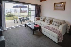 a living room with a couch and a table with an umbrella at 52sq Hawea Apartment, Lake and Mountain views!! in Wanaka