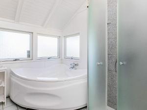 een witte badkamer met een bad en een wastafel bij 6 person holiday home in L kken in Løkken