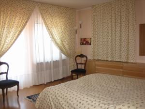 a bedroom with a bed and two chairs and a window at Casa Caterina in Fiera di Primiero