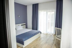 a bedroom with a bed and a chair and a window at Pensiunea Mara in Techirghiol