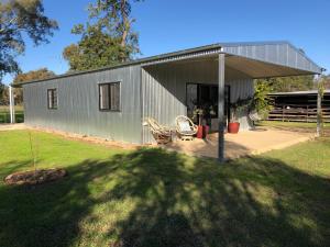 a gray house with a roof and a yard at Oak Lane Guest House & Farm Stay in Whorouly