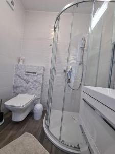 een witte badkamer met een douche en een toilet bij Apartament nad klifem w Dziwnówku in Dziwnówek