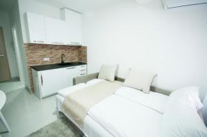 a white bedroom with two beds and a sink at Apartmani Stančić in Banja Koviljača