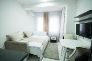 a white living room with a couch and a tv at Apartmani Stančić in Banja Koviljača