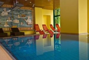 a swimming pool with red chairs and a swimming pool at Thermal Resort Hotel Elisabethpark in Bad Gastein