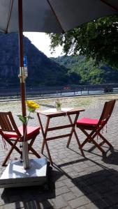 a picnic table and two chairs under an umbrella at Pension / Ferienwohnungen Scheid in Kestert