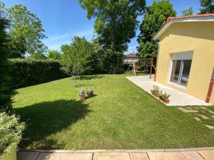 un patio con una casa y un césped con plantas en Chambres dans villa avec piscine, en Gleizé