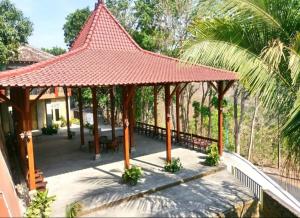 a pavilion with a red roof on top of a house at Bina Karya Guesthouse Syariah in Bantul