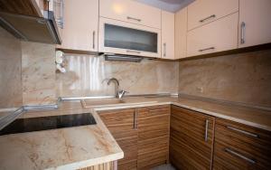 a kitchen with a sink and a tv on the wall at Hotel Mistral in Nesebar
