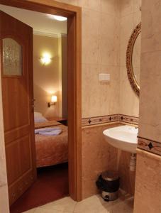 a bathroom with a sink and a bed and a mirror at Pensjonat Beata in Polanica-Zdrój