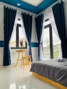 - une chambre avec des rideaux bleus, un lit et une table dans l'établissement November Villa Đà Lạt, à Đà Lạt