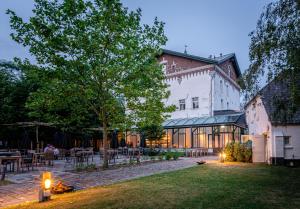 um edifício com um quintal com mesas e cadeiras em Fletcher Hotel Château De Raay em Baarlo