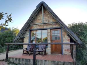 a small stone house with two chairs and a door at Camp Acacia in Paterson