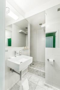 a white bathroom with a sink and a mirror at T-Hotel in Saint Petersburg