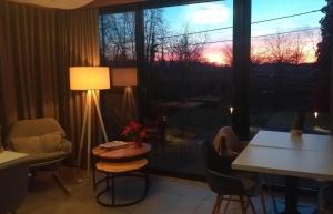 ein Zimmer mit Tisch und Stühlen und einem Fenster mit Blick auf den Sonnenuntergang in der Unterkunft Pluimpapaver Hotel & Glamping in Aarschot
