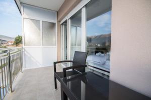 a balcony with a bed and a glass table and chair at Apartmani Pantovic - Apartman 2 in Trebinje +3 photos