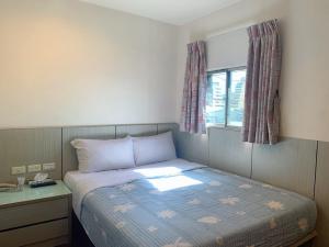 um pequeno quarto com uma cama e uma janela em Ruei Gung Business Hotel Kaohsiung em Kaohsiung