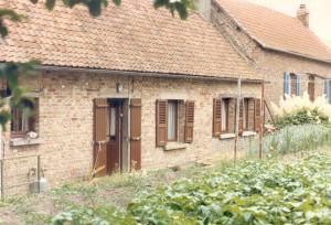 an old brick house with brown shutters on it at La maison de Pierre et Liliane in Crouy +2 photos