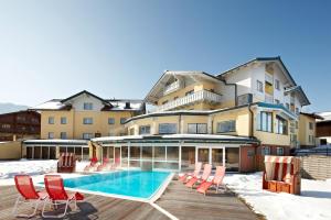 a house with a swimming pool and chairs in the snow at Hotel Moser in Schladming