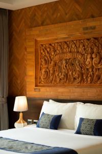 a bedroom with a wooden headboard and a bed at Phor Liang Meun Terracotta Arts in Chiang Mai