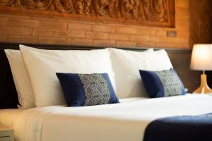a bed with blue and white pillows at Phor Liang Meun Terracotta Arts in Chiang Mai
