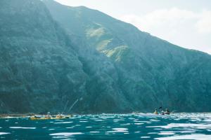 a group of people kayaking in the water near a mountain at THE STAY WAKKANAI in Wakkanai