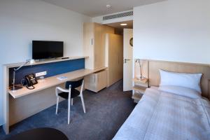 Habitación de hotel con cama y escritorio con TV. en Hotel Erwin Junker en Holice