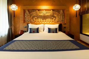 a bedroom with a white bed with a wooden headboard at Phor Liang Meun Terracotta Arts in Chiang Mai