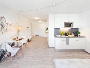 uma cozinha e sala de jantar com armários brancos e uma mesa em NEU☆Business Apartment☆Messe/Airport☆Tiefgarage em Leinfelden-Echterdingen