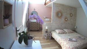 a bedroom with a bed and a dresser and a plant at Gîte de La Pilotais in Pleslin-Trigavou