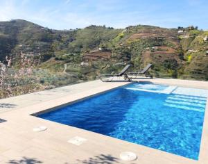 una piscina con 2 sillas frente a una montaña en Villa Serena - amazing villa with private pool, en Cómpeta