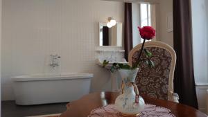 a bathroom with a table with a vase with a rose in it at La Maison Serrurier - Chambres d’hôtes in Morlaix