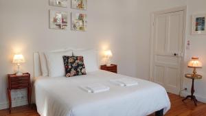 a white bed in a room with two lamps at La Maison Serrurier - Chambres d’hôtes in Morlaix