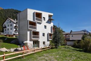 a white building on a hill next to a house at Alpine Lodge Chesa Plattner in Pontresina