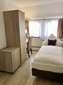 a bedroom with a bed and a cabinet and a desk at A Lotus Hotel in Böblingen