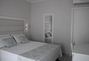 a white bedroom with a bed and a mirror at La Guitgia Rooms in Lampedusa