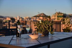 una mesa con dos copas y una botella de vino en Greece U Around Athens Thissio Suites, en Atenas