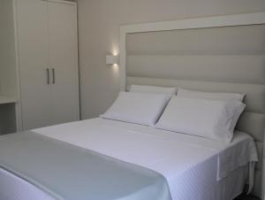 a white bed with white sheets and pillows at La Guitgia Rooms in Lampedusa