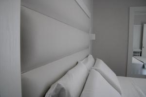 a white bed with white pillows in a bedroom at La Guitgia Rooms in Lampedusa