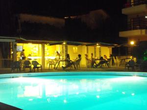 a swimming pool at night with people sitting around a table at Le Mirage Hotel in Benitses