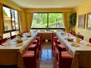 una grande sala da pranzo con tavoli lunghi e sedie rosse di La Bastia Hotel & Resort a Soriano nel Cimino