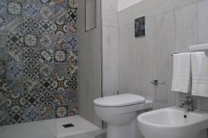 a white bathroom with a toilet and a sink at La Guitgia Rooms in Lampedusa